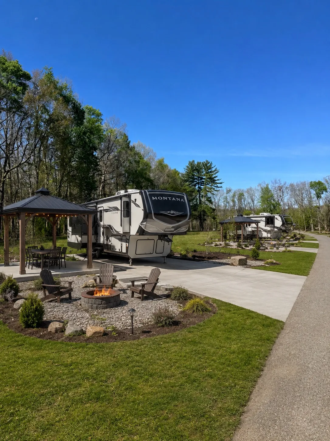 Concept rendering of a Premium RV site: a fifth-wheel beside a pergola with string lights and Adirondack chairs around a fire pit, framed by trees.